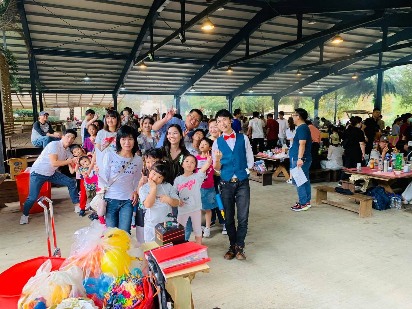 戶外棚架下大人小孩圍著穿藍背心的氣球達人柯男合照