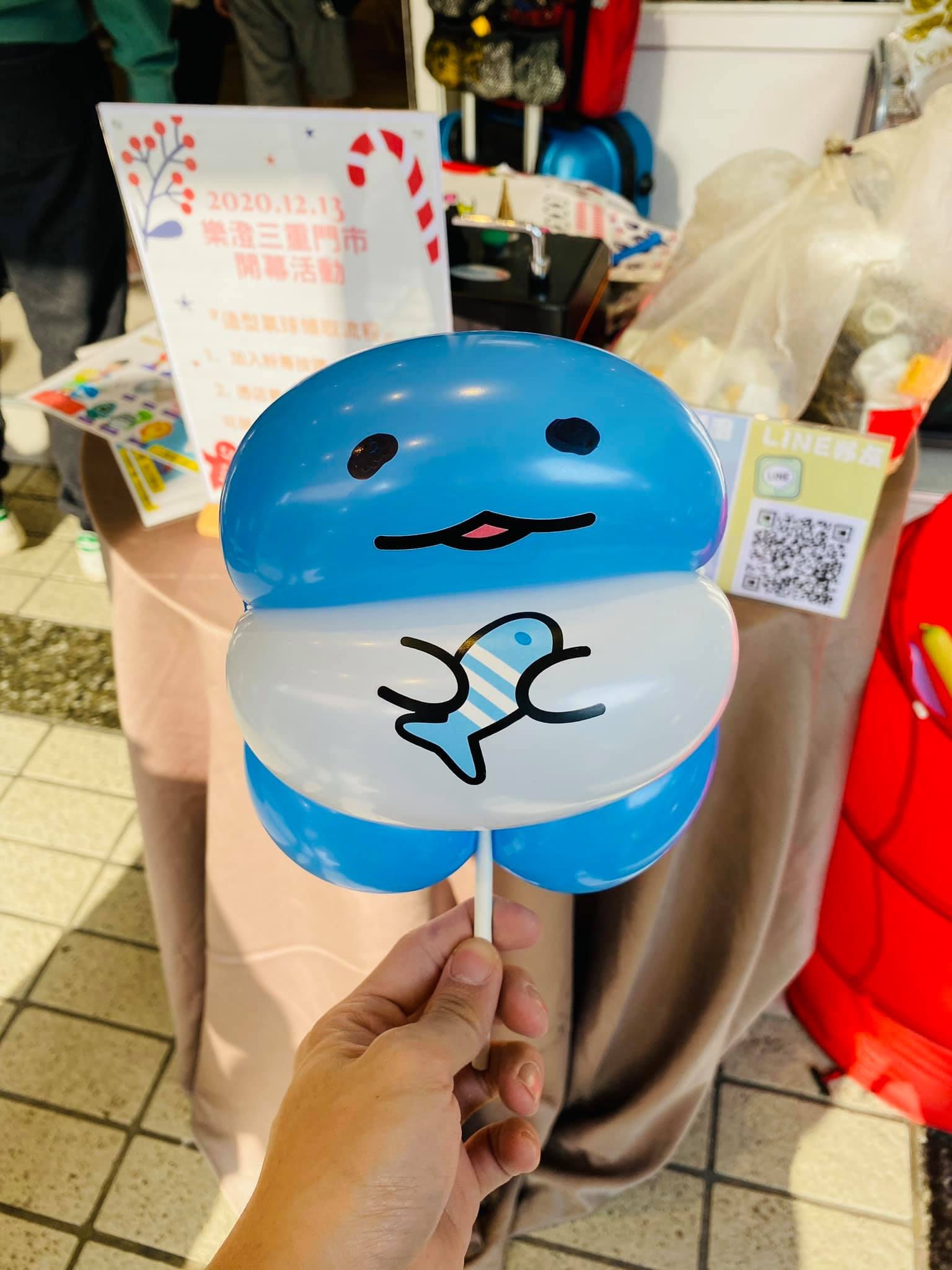 藍白色抱著小魚的圓形角色氣球，後方是開幕活動立牌