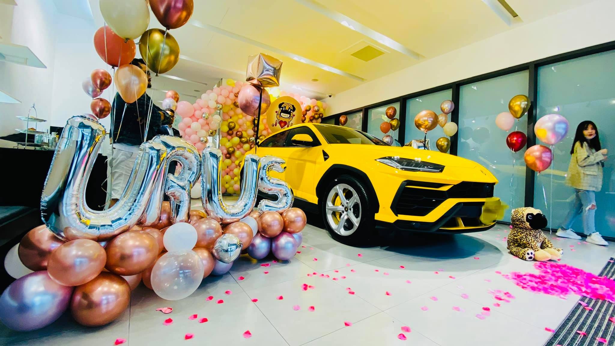廣角拍攝的汽車展間交車佈置，氣球束圍繞黃色 URUS