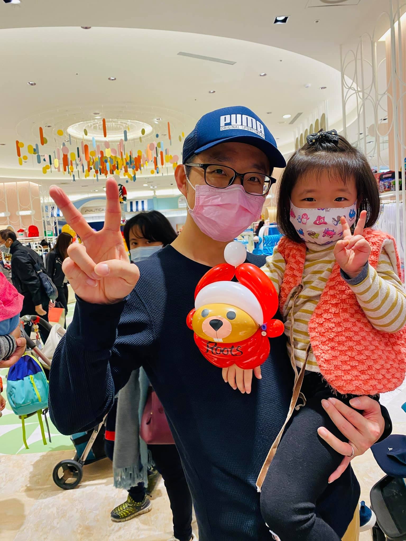 爸爸抱著女兒,手拿戴聖誕帽的紅色海狸氣球