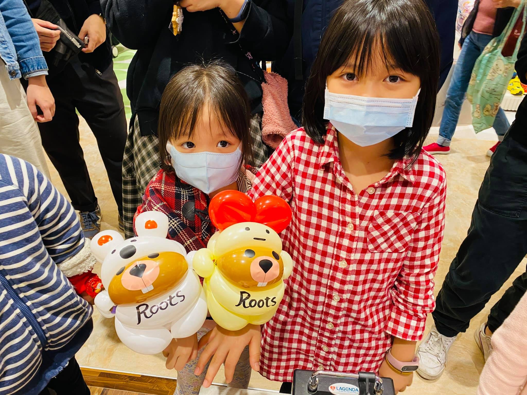 兩個女孩拿著白色和戴紅蝴蝶結黃色海狸氣球