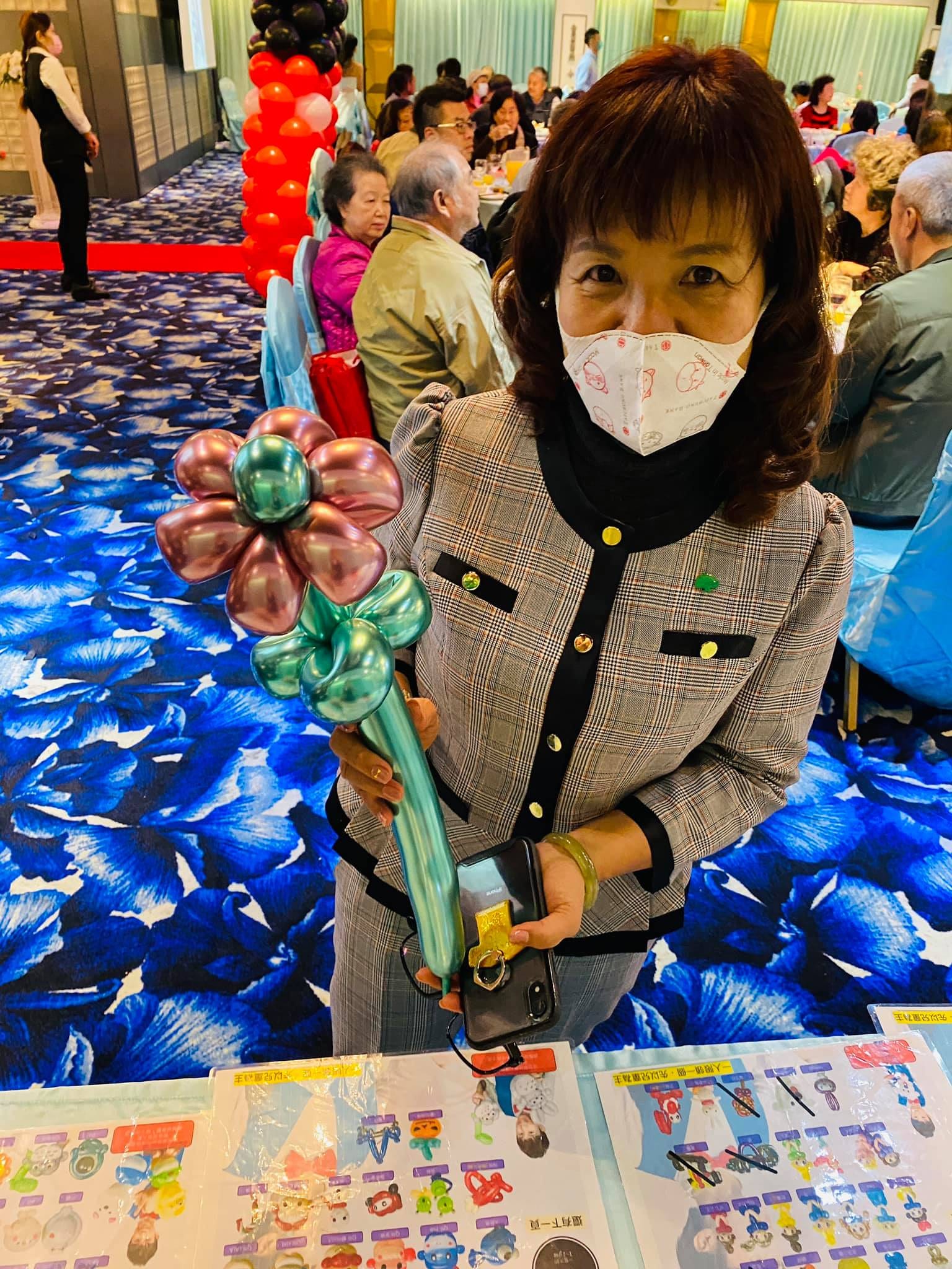 戴口罩的女士賓客拿著粉紅花朵造型氣球
