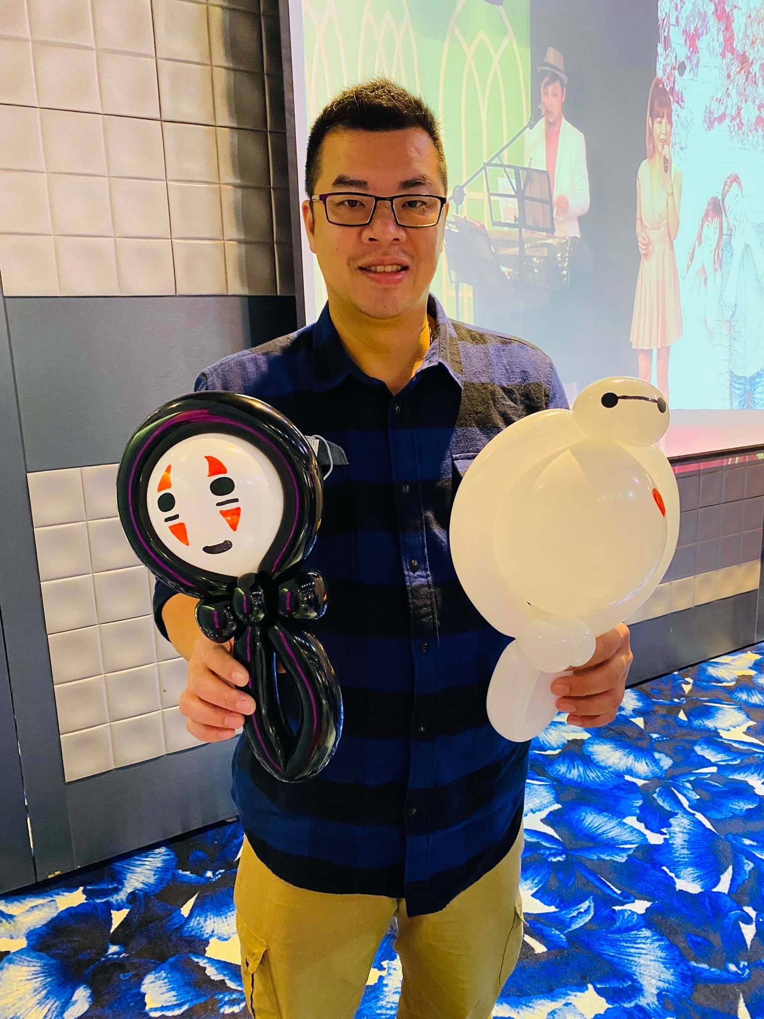 男士雙手拿著無臉男與杯麵造型氣球站在宴會廳