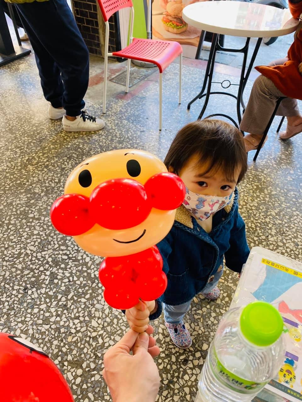 戴口罩的小小孩看著眼前的麵包超人造型氣球