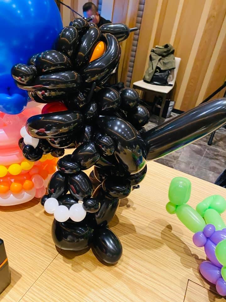 黑色哥吉拉造型氣球立在派對桌上，背鰭與尾巴清楚