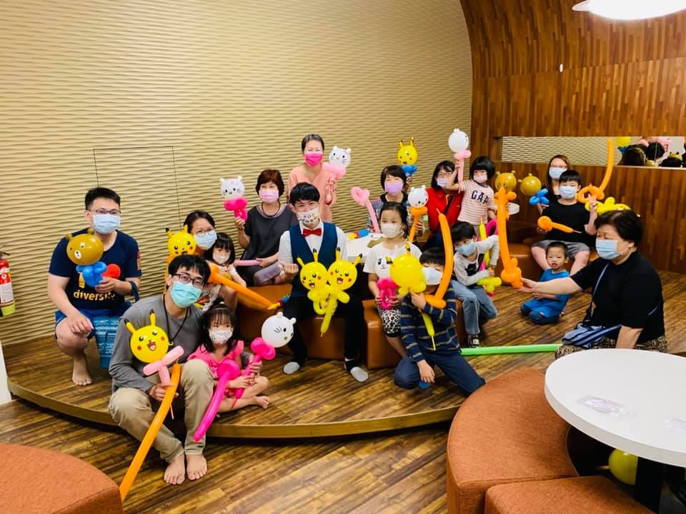 室內木地板空間，親子拿著造型氣球和柯男大合照