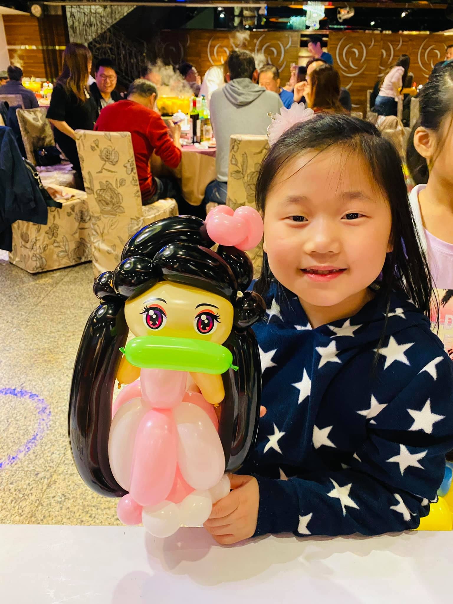 穿星星毛衣的女孩抱著禰豆子造型氣球露出笑容