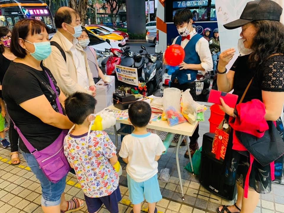4月初的街邊氣球攤位，柯男拿著紅色氣球招呼親子