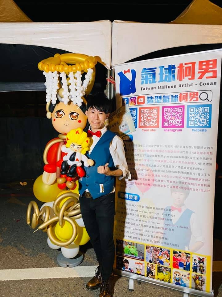 柯男站在即興氣球媽祖旁，媽祖戴金色冠冕、穿紅色衣袍