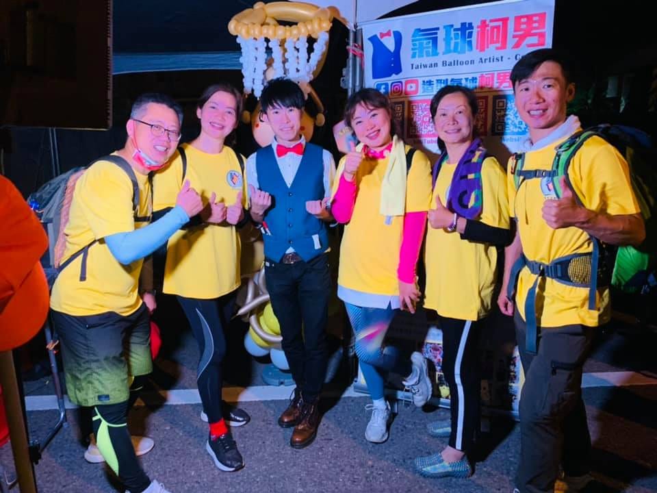一群穿黃色上衣的進香團員和柯男在攤位前合照