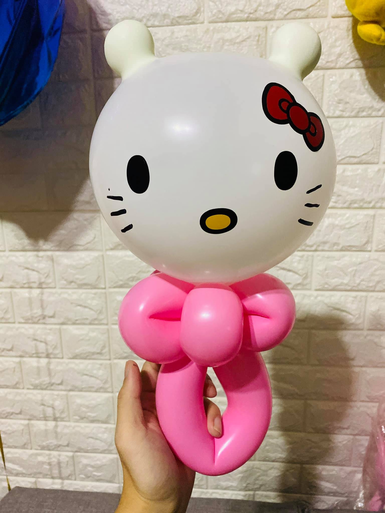 Hello Kitty 手持氣球，白色圓臉、紅色蝴蝶結、白色耳朵，下面接粉紅蝴蝶結與握把