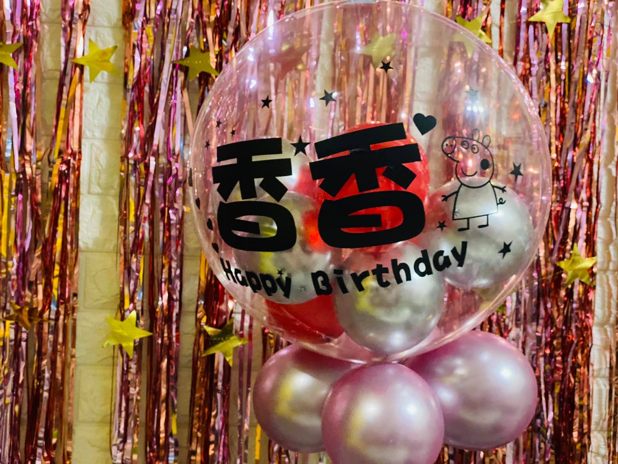 印上小名與 Happy Birthday 的客製透明氣球，底座為粉色珠光氣球