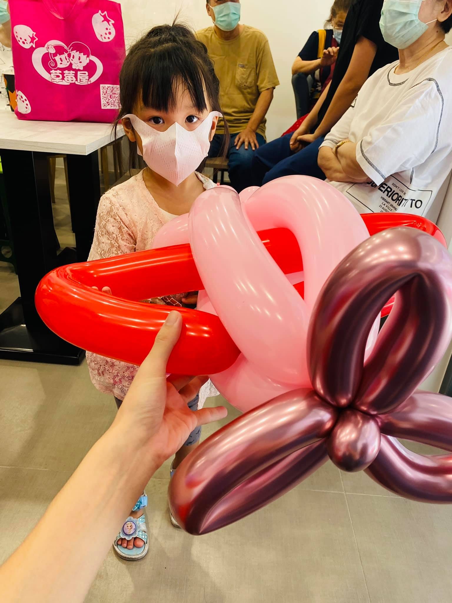 小女孩面前的紅色愛心與粉紅、玫瑰紅花朵組合氣球