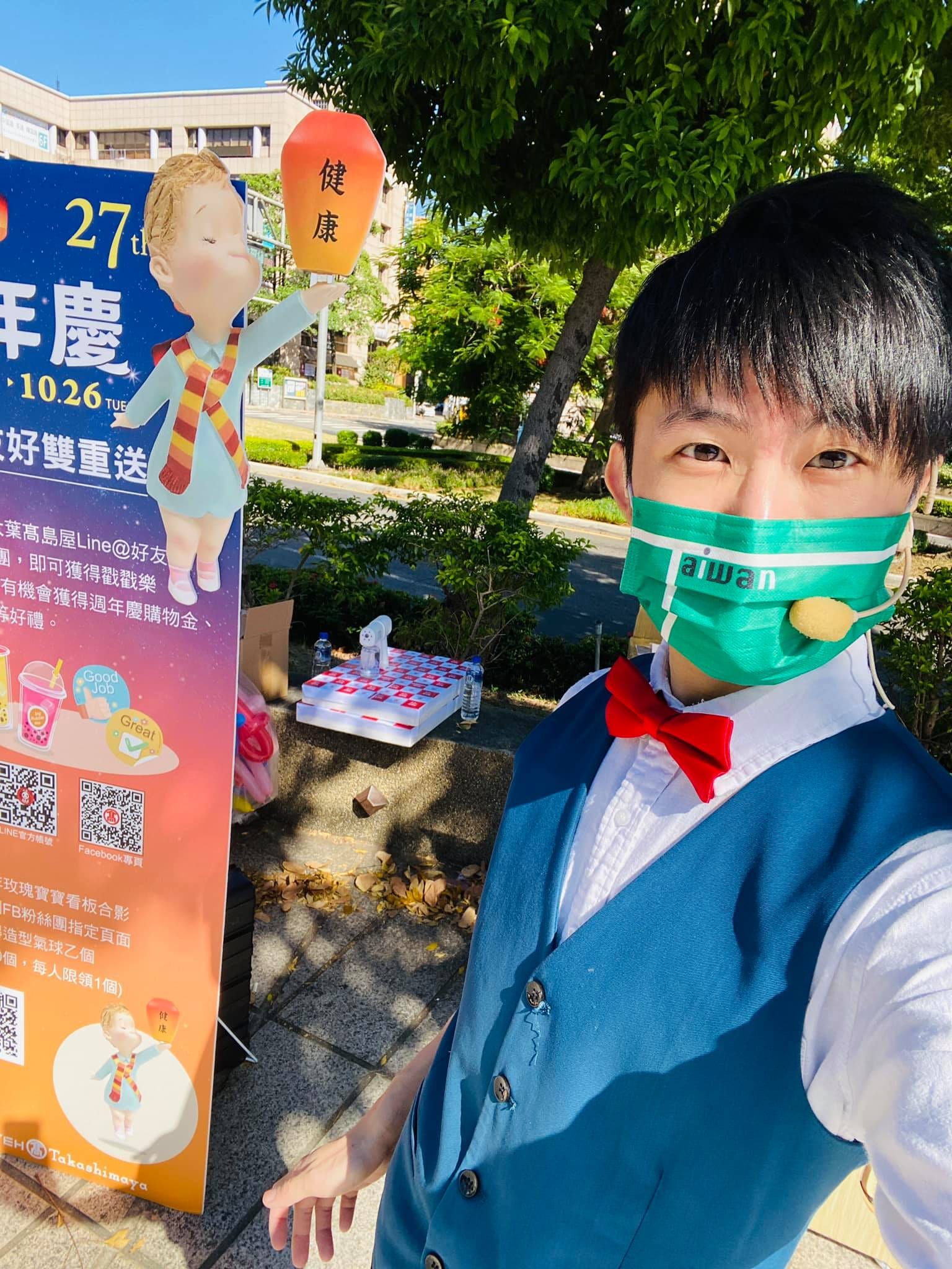 柯男戴著耳麥在大葉高島屋 27 週年慶立牌旁自拍