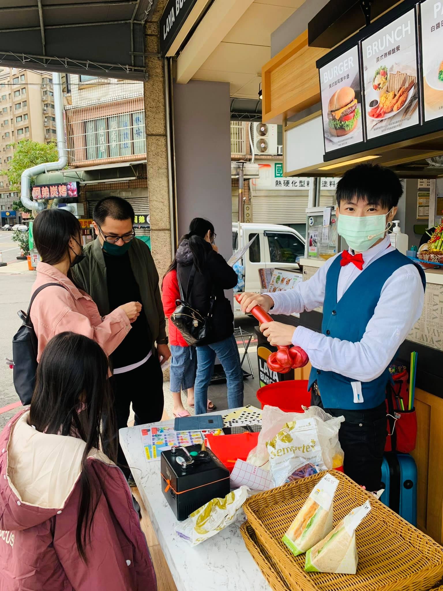 拉亞漢堡門市騎樓的折氣球攤位，柯男正在折紅色氣球