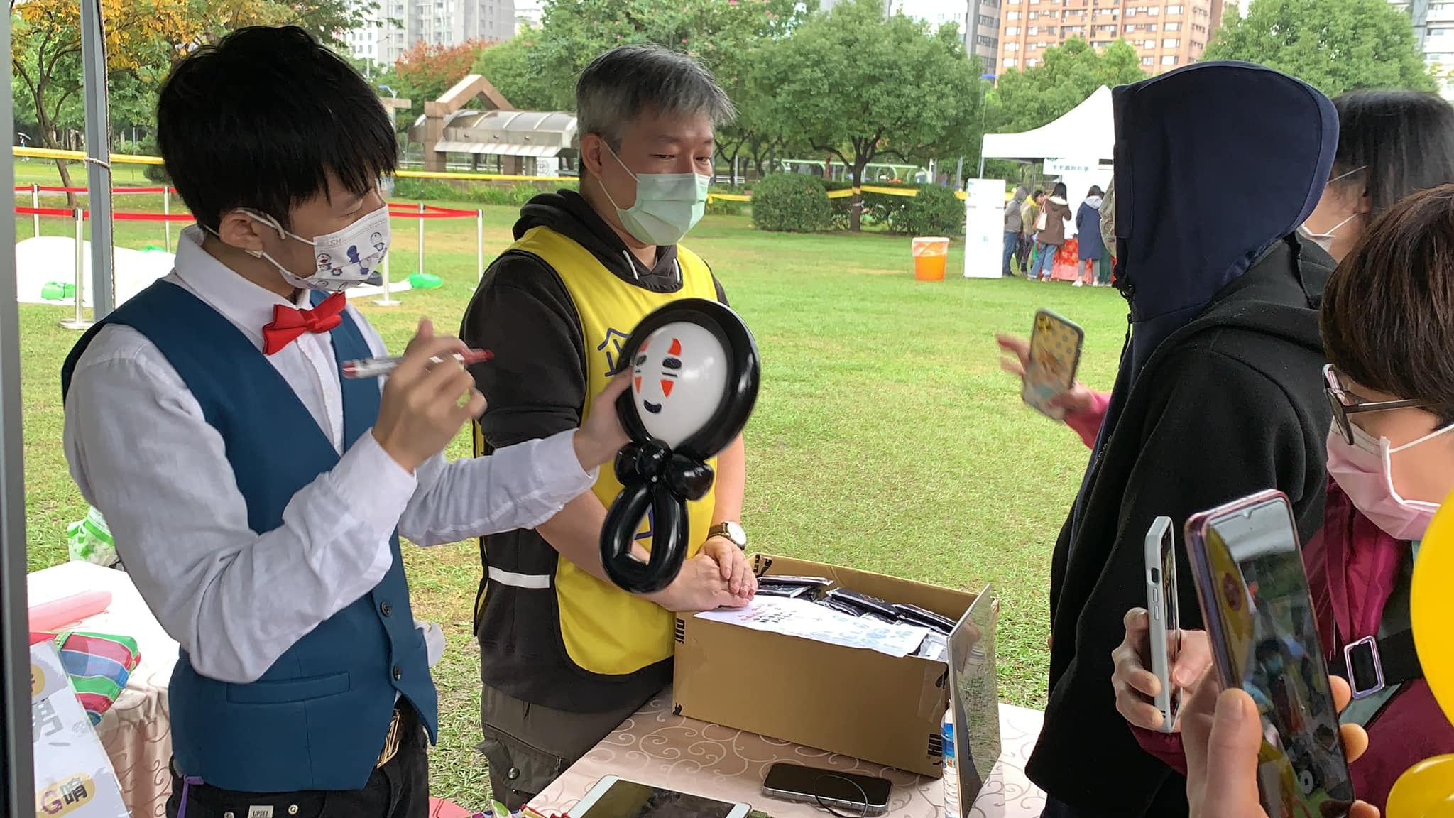 柯男在攤位替黑色無臉男氣球畫上表情