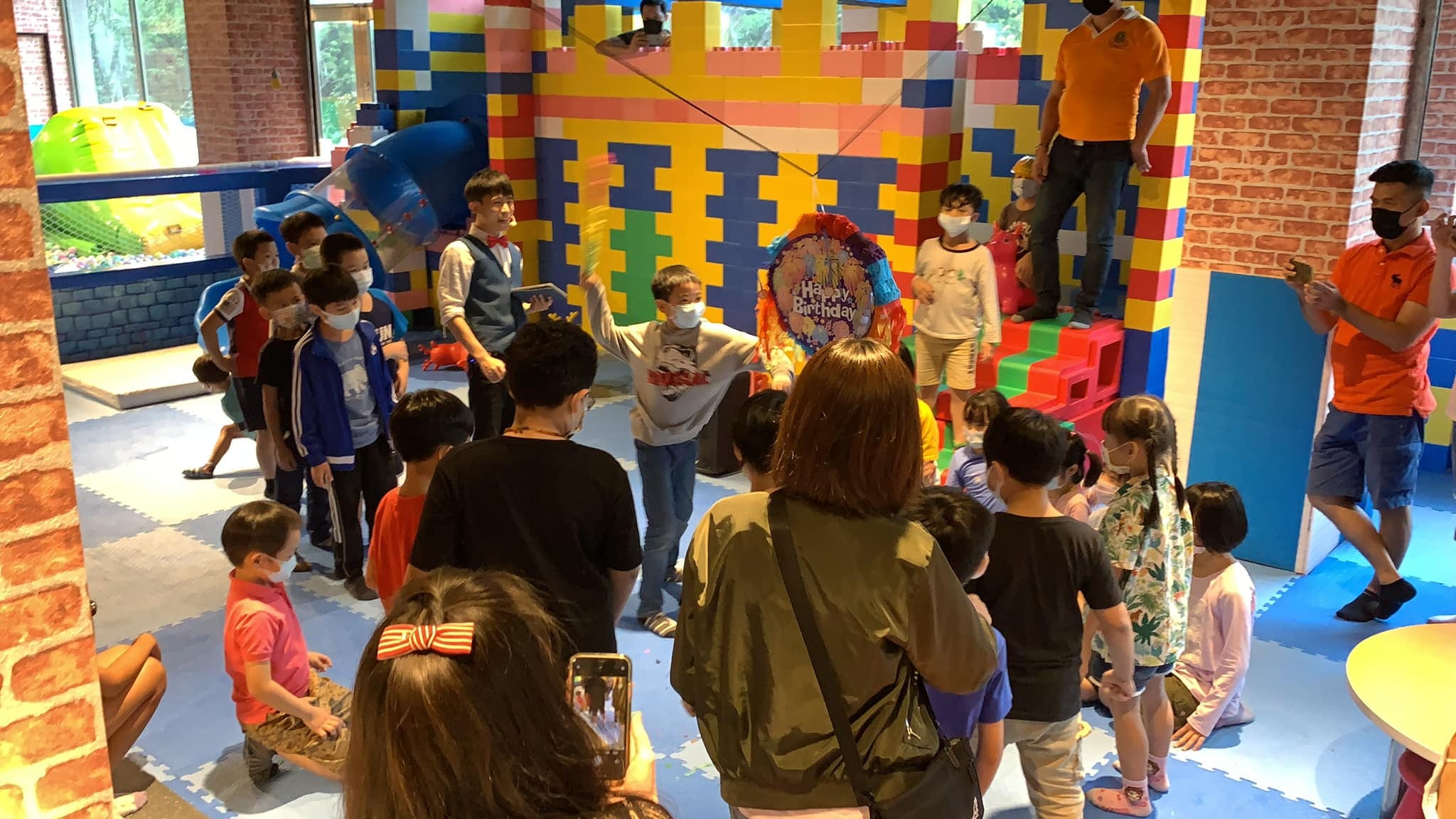積木牆遊戲區裡，小朋友拿棒子輪流打 Happy Birthday 皮納塔