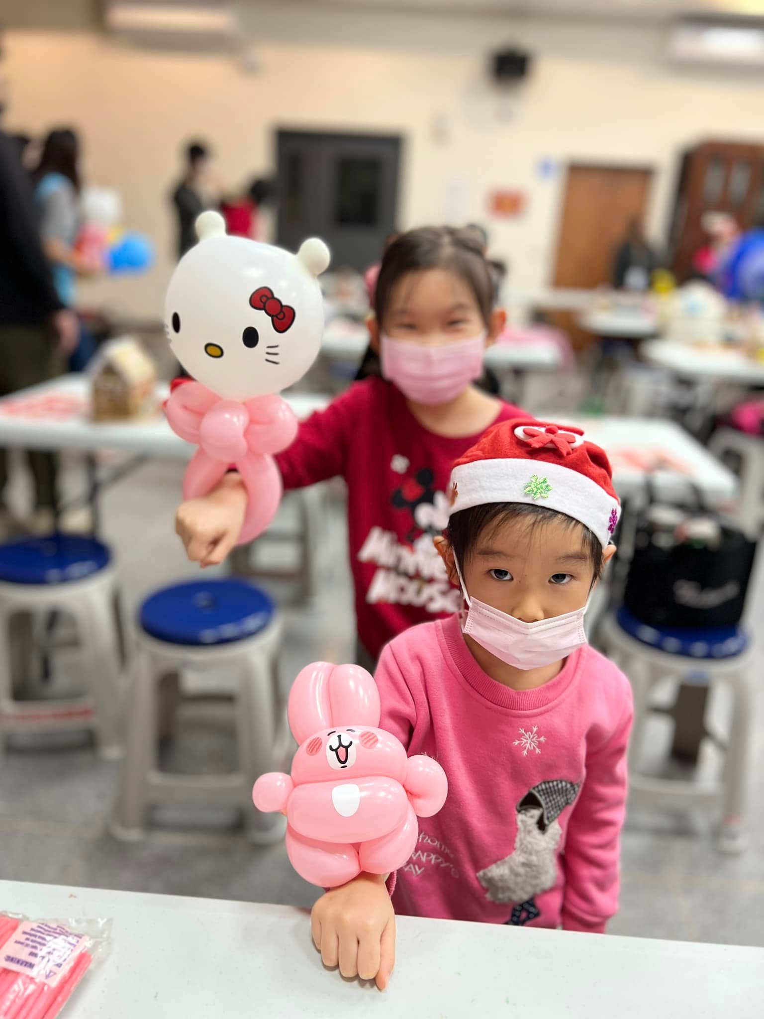 兩個小女孩手腕上套著 Hello Kitty 與粉紅兔子造型氣球