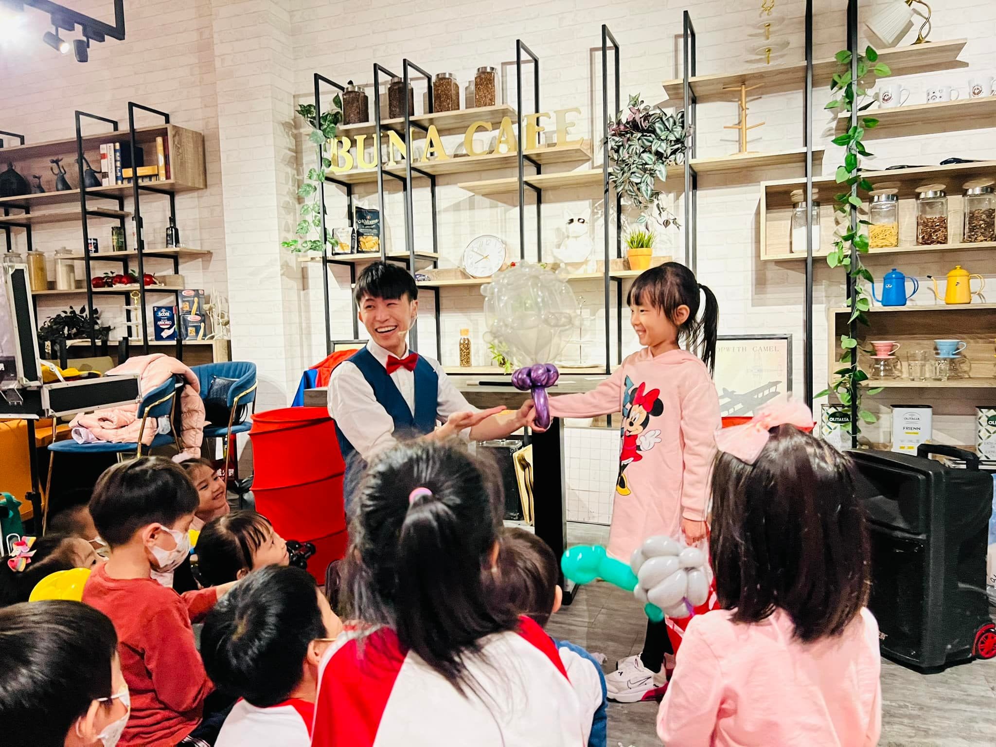 台北內湖 BUNA CAFE 裡，柯男把氣球魔術道具交給穿粉紅上衣的女孩