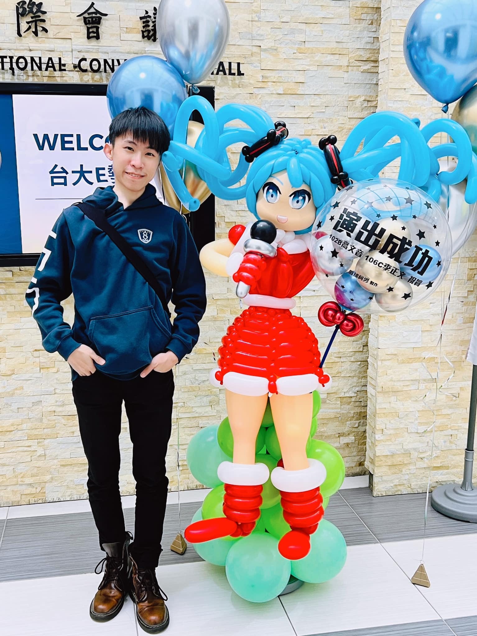 穿聖誕紅裙拿麥克風的初音未來氣球人偶，旁有演出成功透明氣球