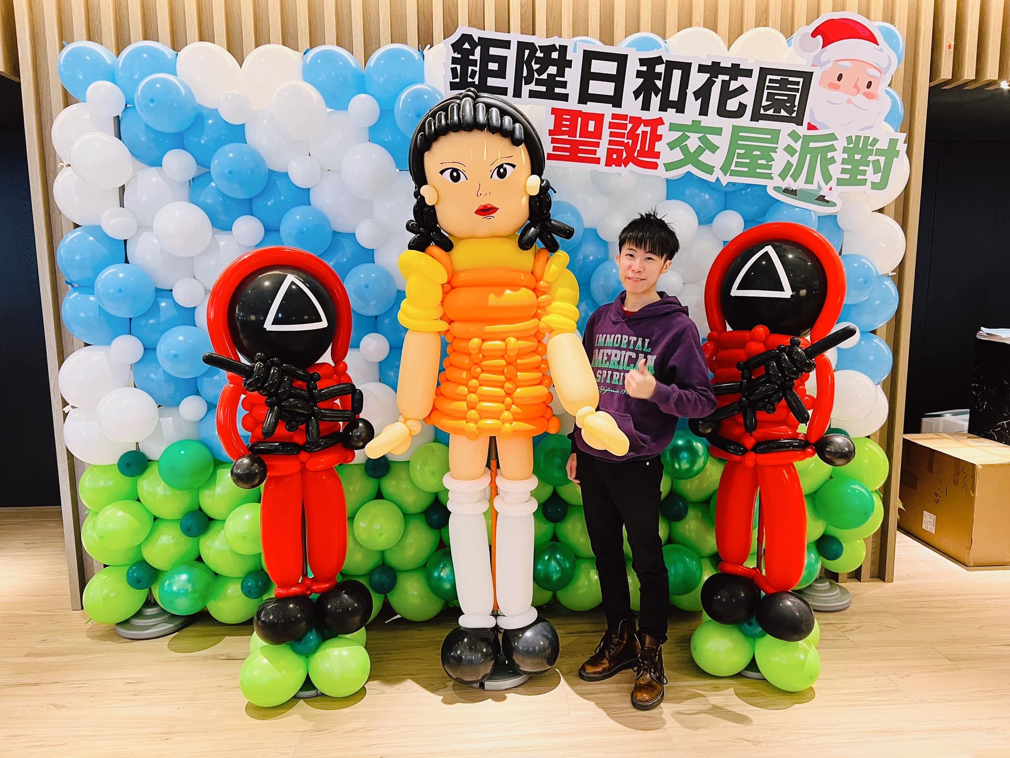 藍白綠氣球牆前的魷魚遊戲木頭人娃娃與兩隻士兵氣球人偶