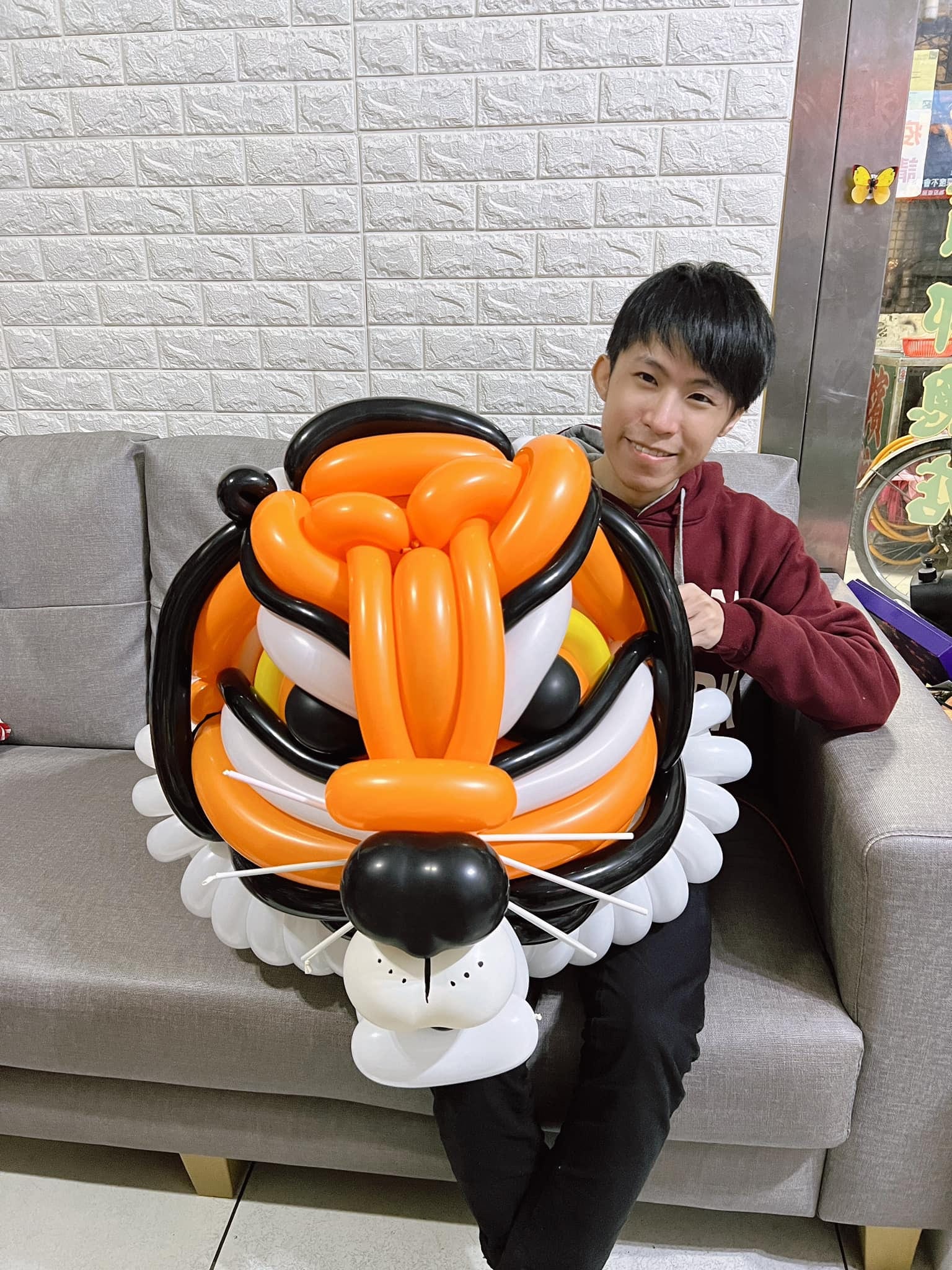 柯男坐在沙發上抱著大型老虎頭造型氣球