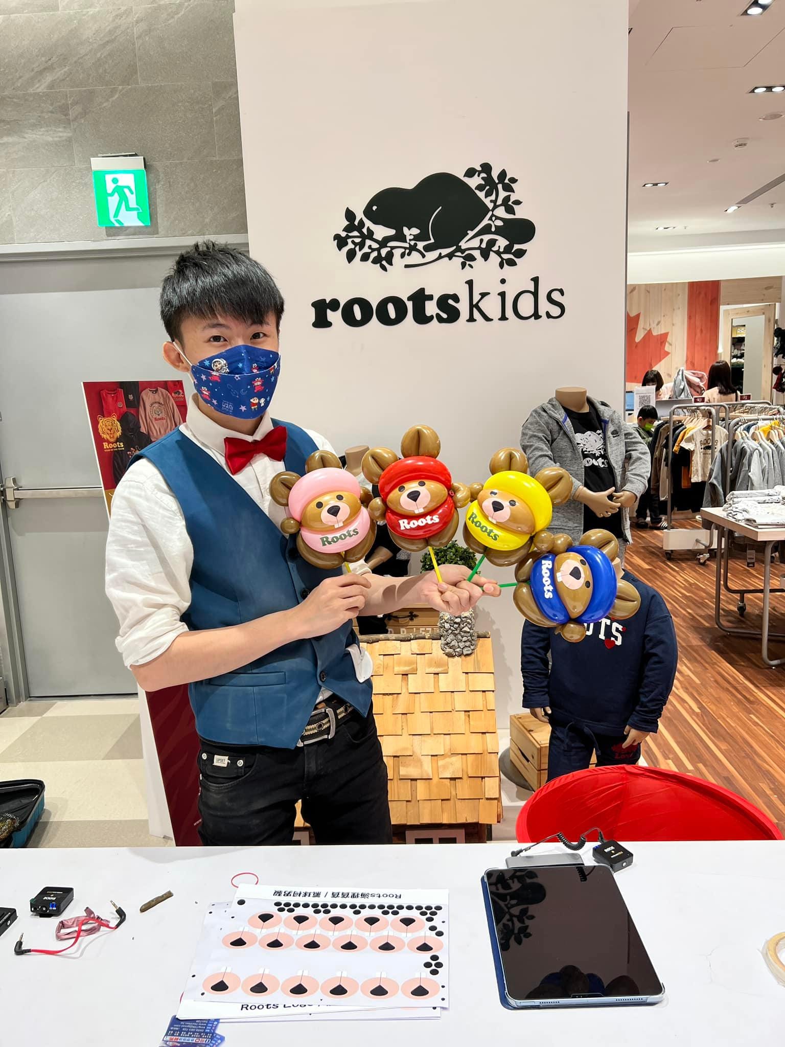 柯男在 Roots Kids 櫃位前拿著四隻不同帽色的海狸寶寶氣球