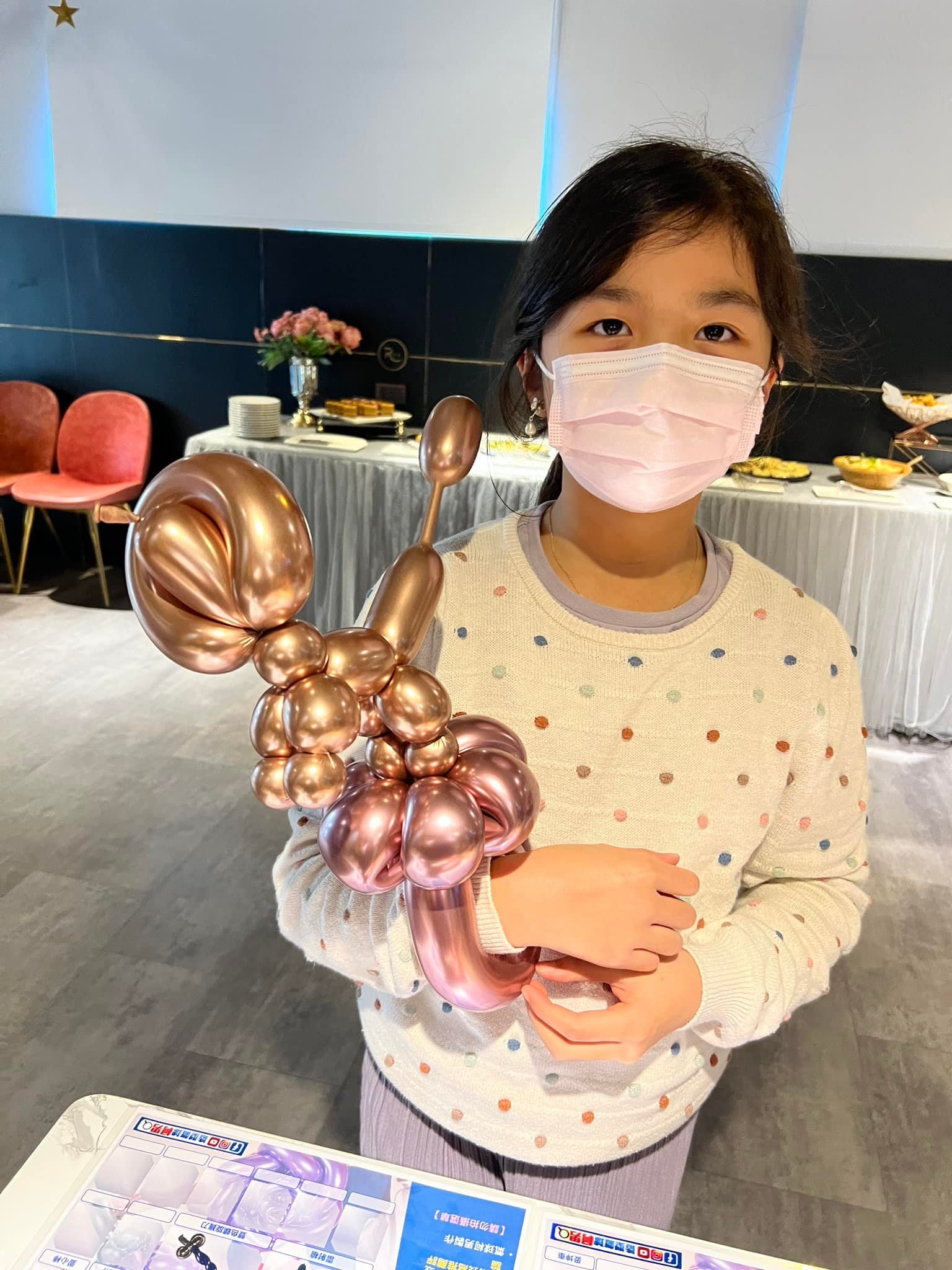 小女孩手上套著玫瑰金亮面貴賓狗造型氣球
