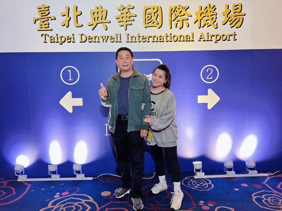 柯爹與賓客在機場出境主題拍照牆前比讚合照