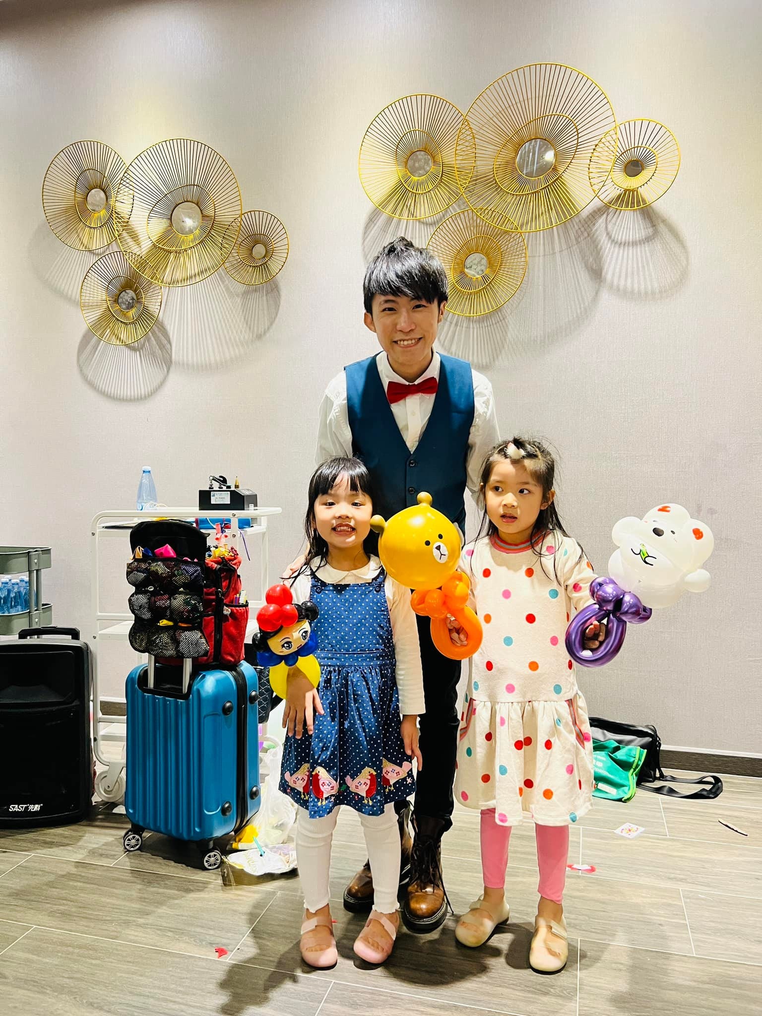 兩位小女孩拿著黃色小熊與白色小熊氣球，和柯男合照