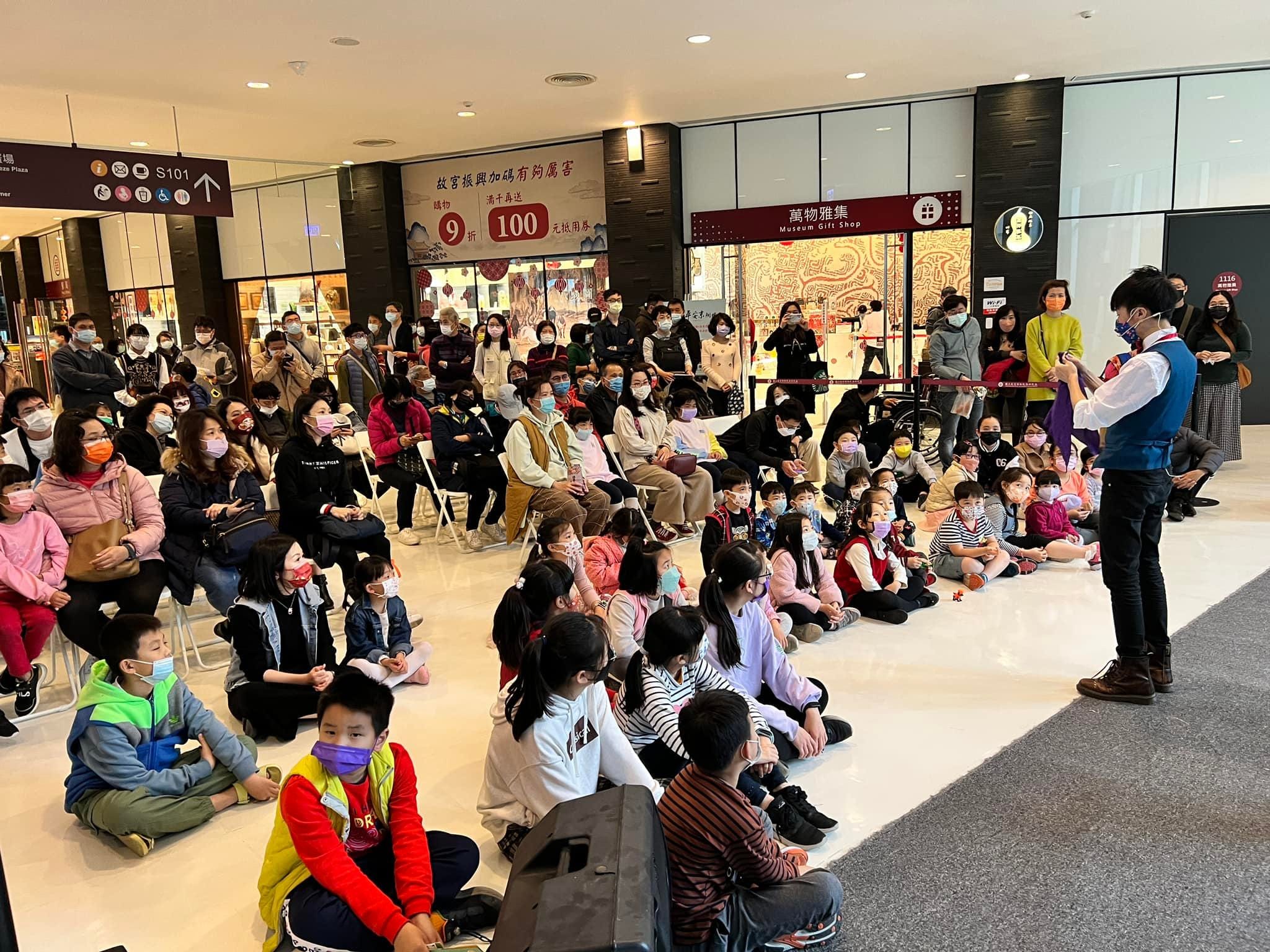 柯男在故宮南院禮品店前表演魔術，地上放著章魚造型氣球
