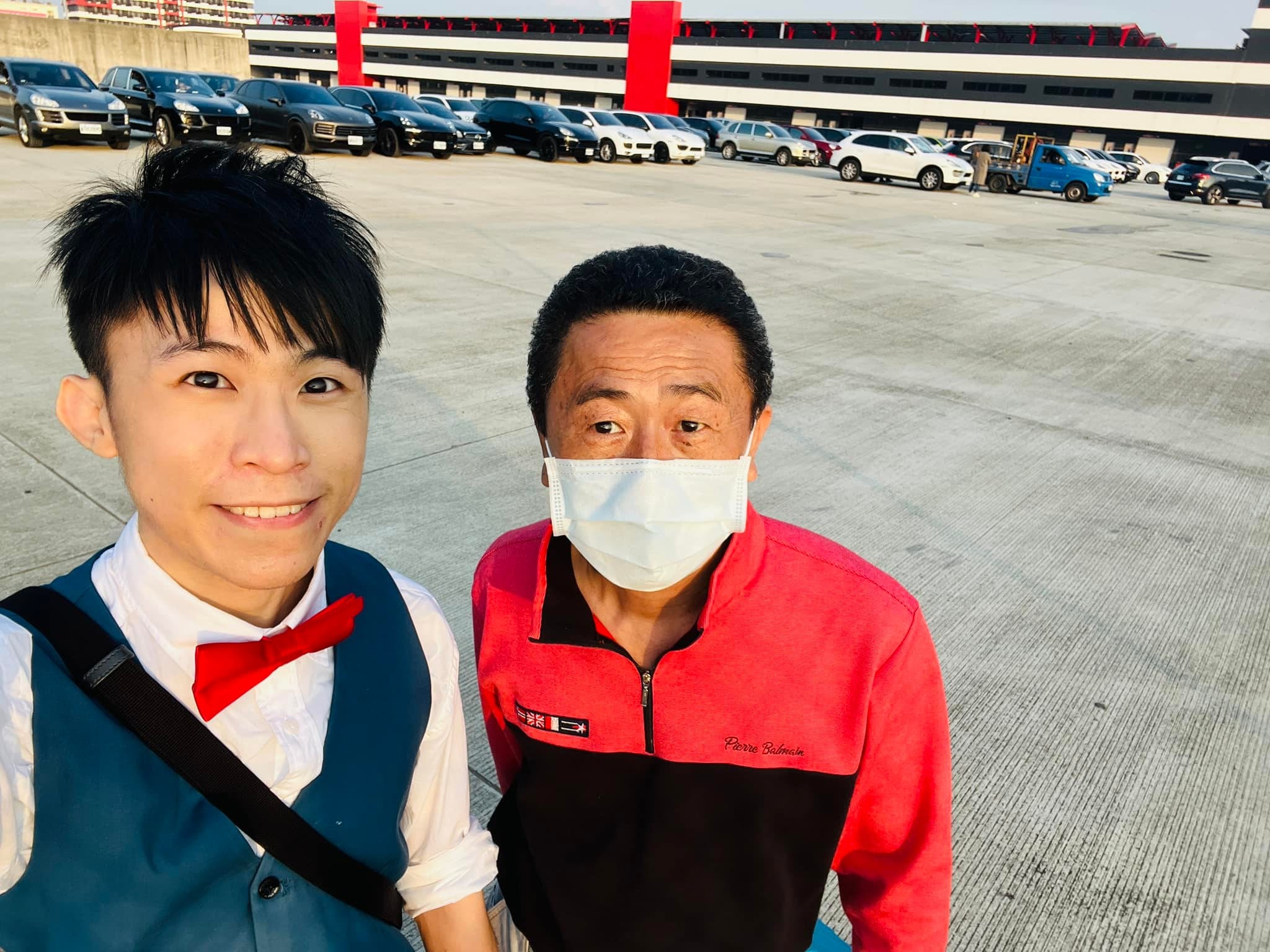 柯男與柯爹在賽車場停車場自拍，後方停滿保時捷休旅車