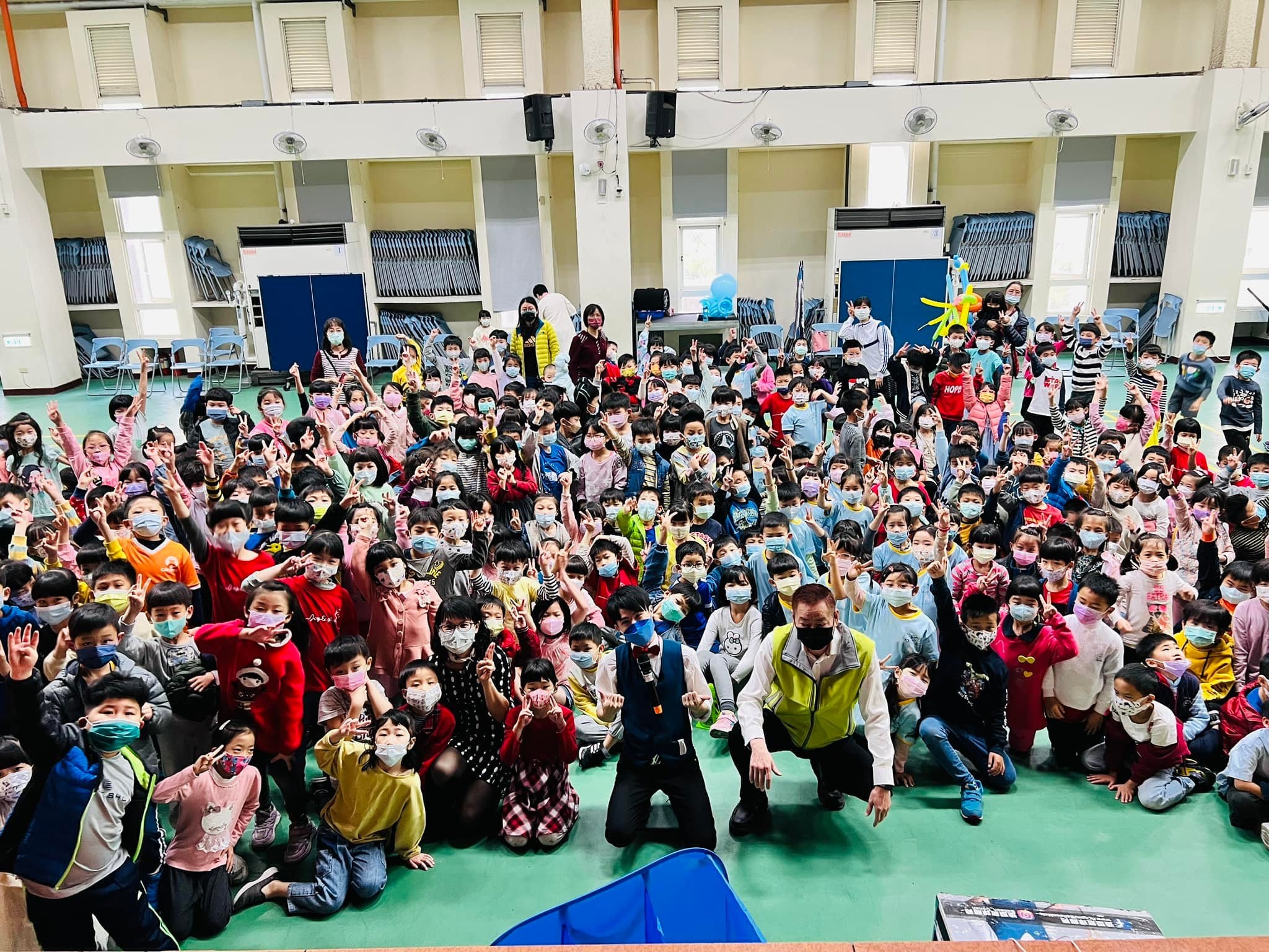 國安國小低年級學生揮手合照,地上放著魔術道具箱