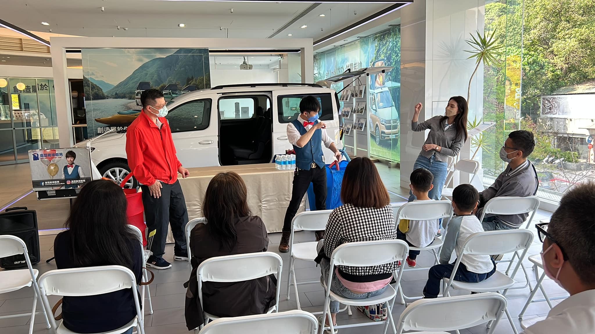 太古福斯展間內,柯男在白色休旅車前替來賓表演魔術