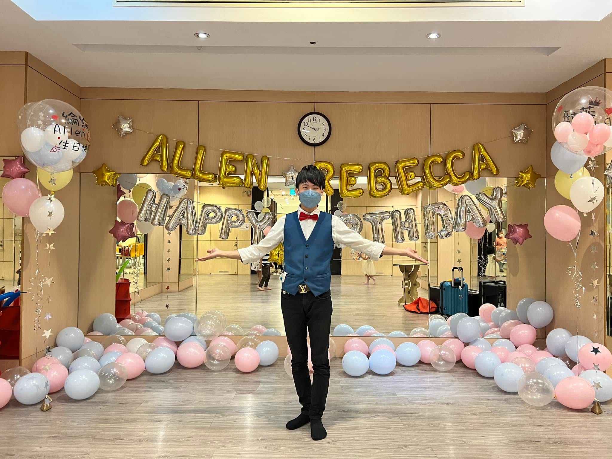 柯男站在金色名字字母與銀色生日字母前，地面鋪滿粉藍氣球