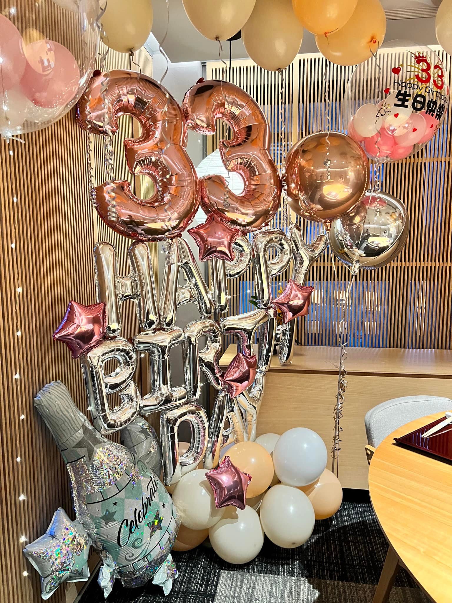 玫瑰金數字 33 與銀色 HAPPY BIRTHDAY 字母氣球，旁有香檳瓶