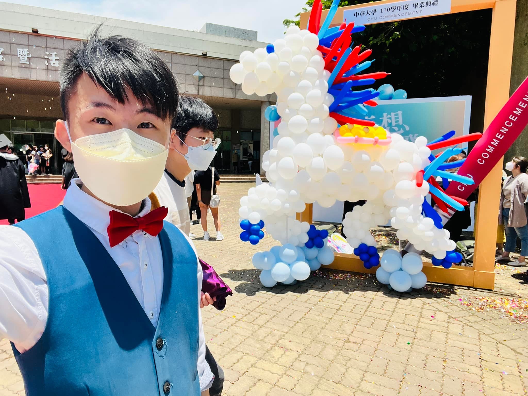 柯男在校園戶外自拍,身後是揚起前蹄的白色氣球馬