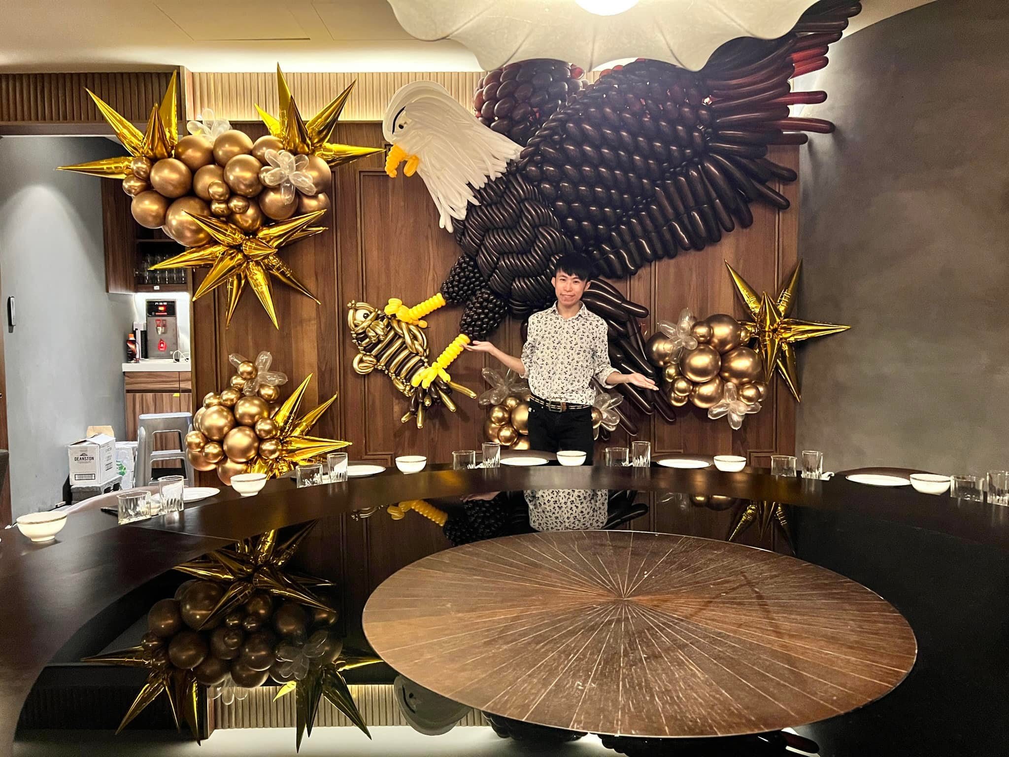 餐廳包廂木牆上展翅的立體老鷹氣球雕塑,兩側是金色爆炸星
