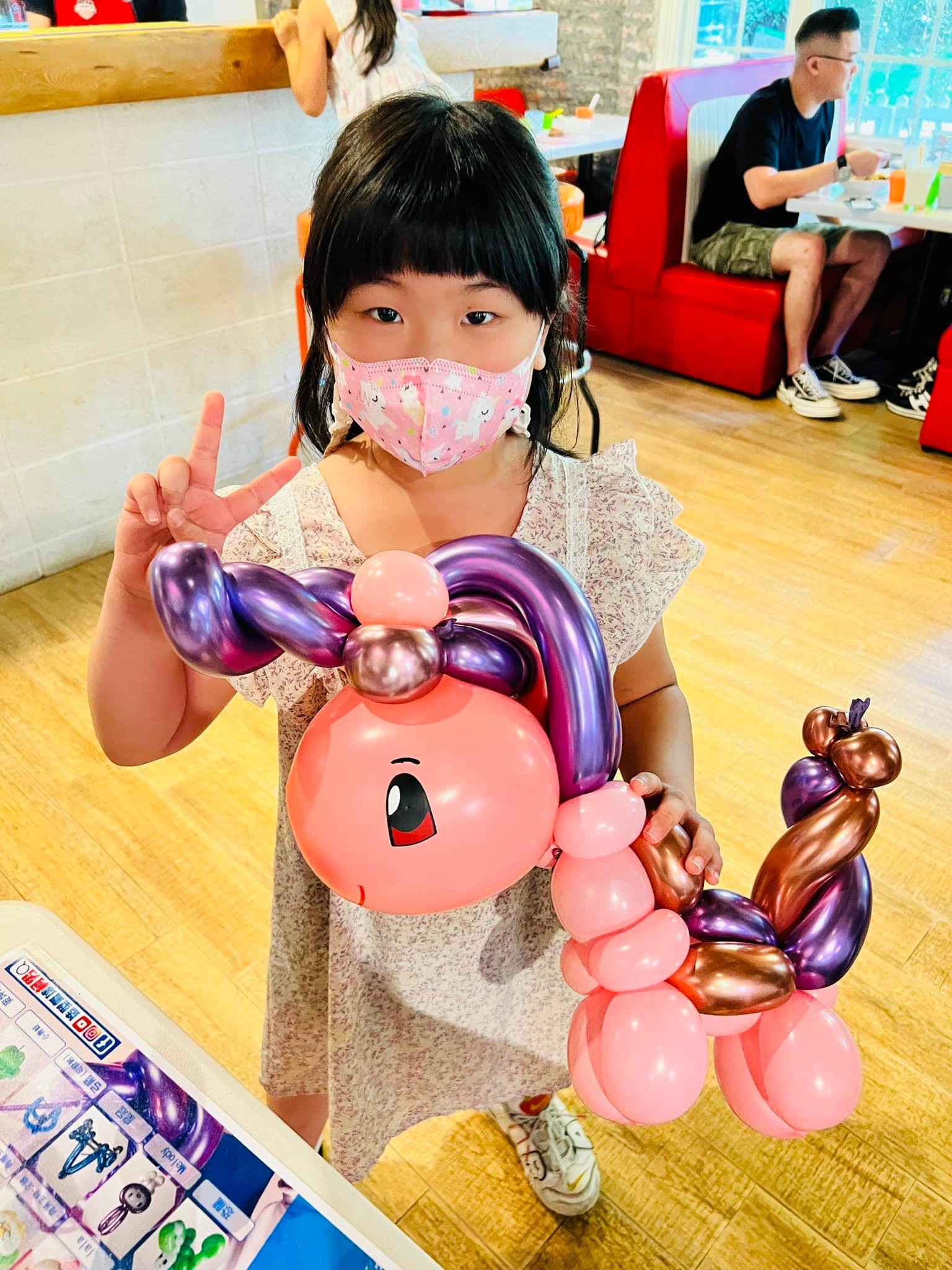 女孩比 YA，抱著粉紅身體、紫色鬃毛的獨角獸氣球