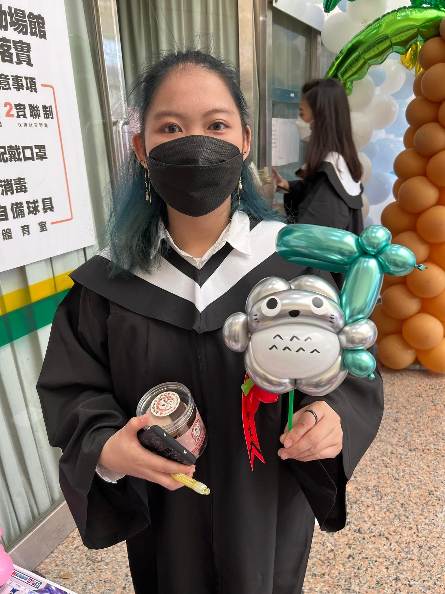穿學士服的畢業生拿著銀灰色龍貓造型氣球