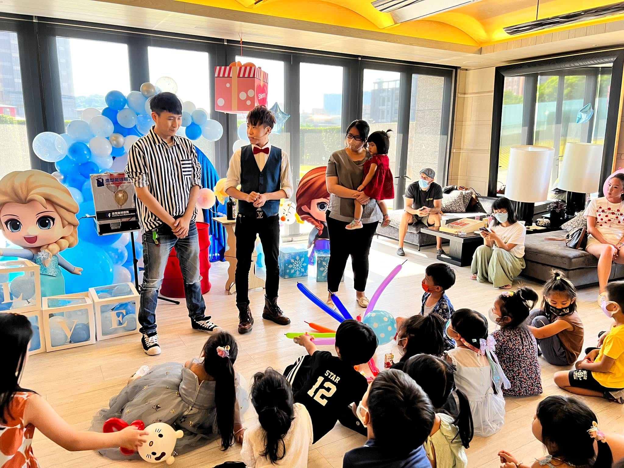 柯男與一位穿條紋上衣的表演者站在場中,孩子們拿著氣球劍圍坐