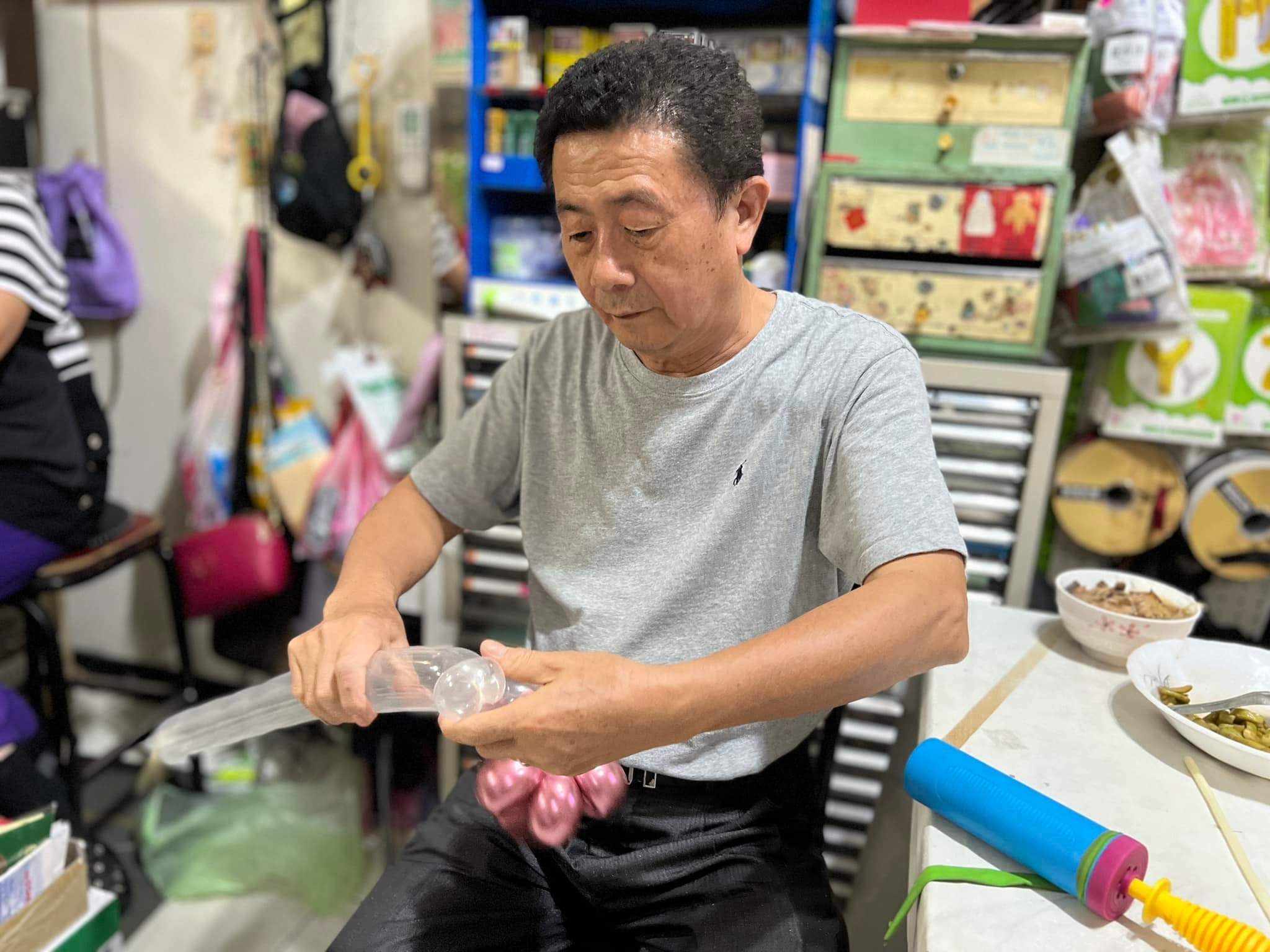 柯爹坐在堆滿材料的工作室裡,專心把透明氣球套進粉紅氣球
