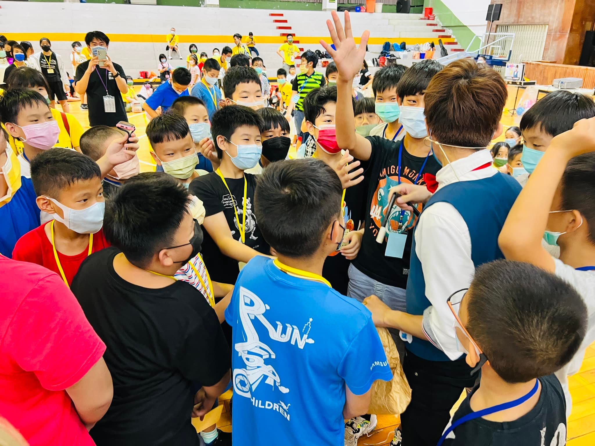 掛著名牌的孩子們圍著柯男，伸手看他手上的魔術道具