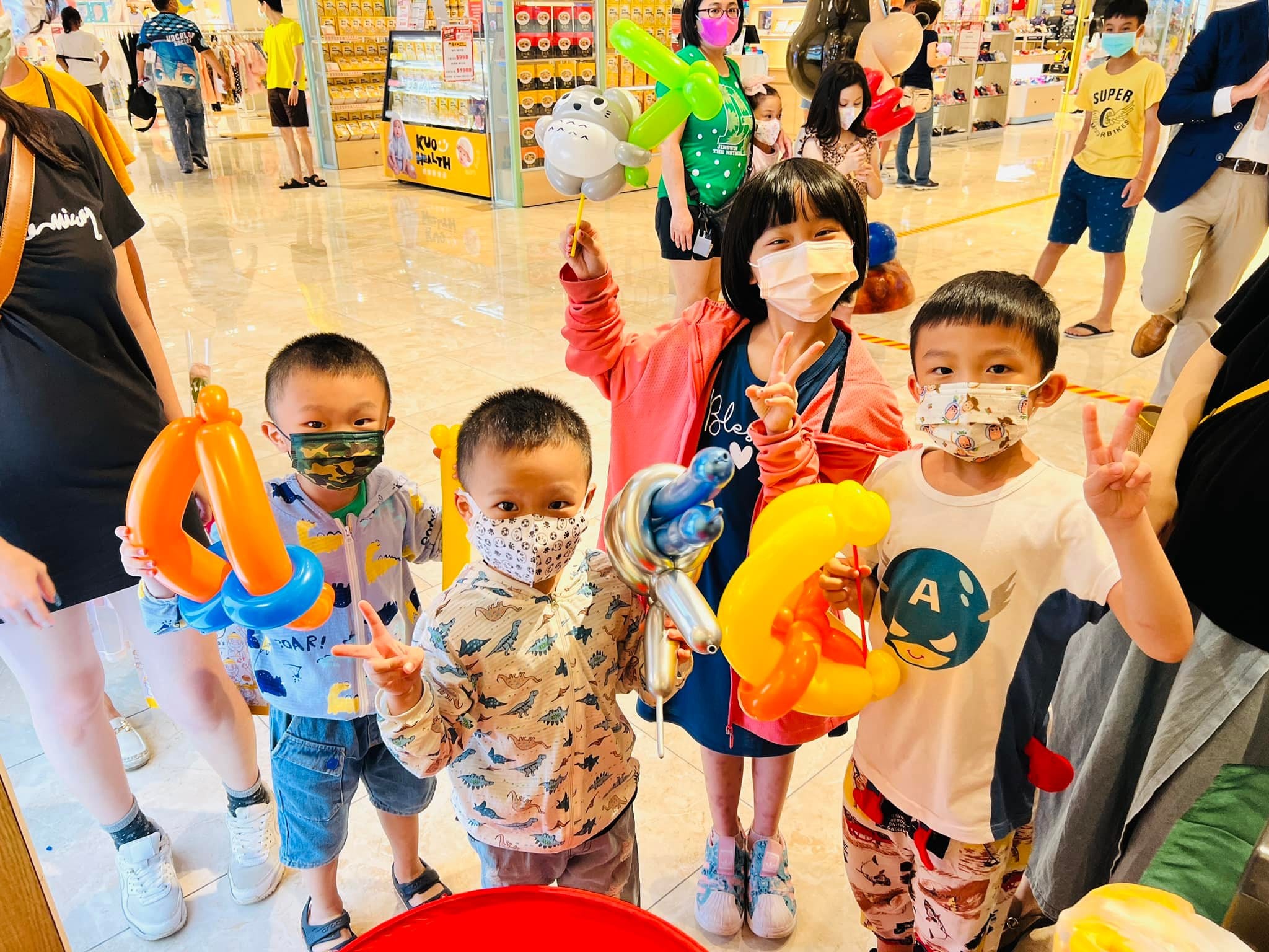 一群孩子在商場大廳拿著各種造型氣球比 YA 合照