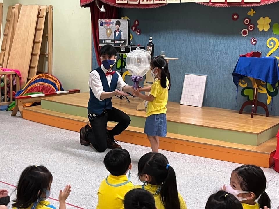柯男單膝跪地，和穿黃色園服上台的小女孩一起完成透明球魔術