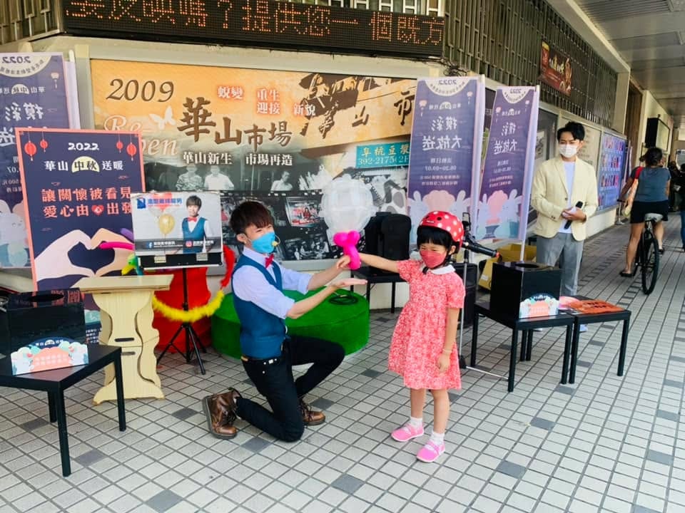 台北中正公益募款活動,柯男單膝跪地和戴紅色安全帽的小女孩一起變魔術