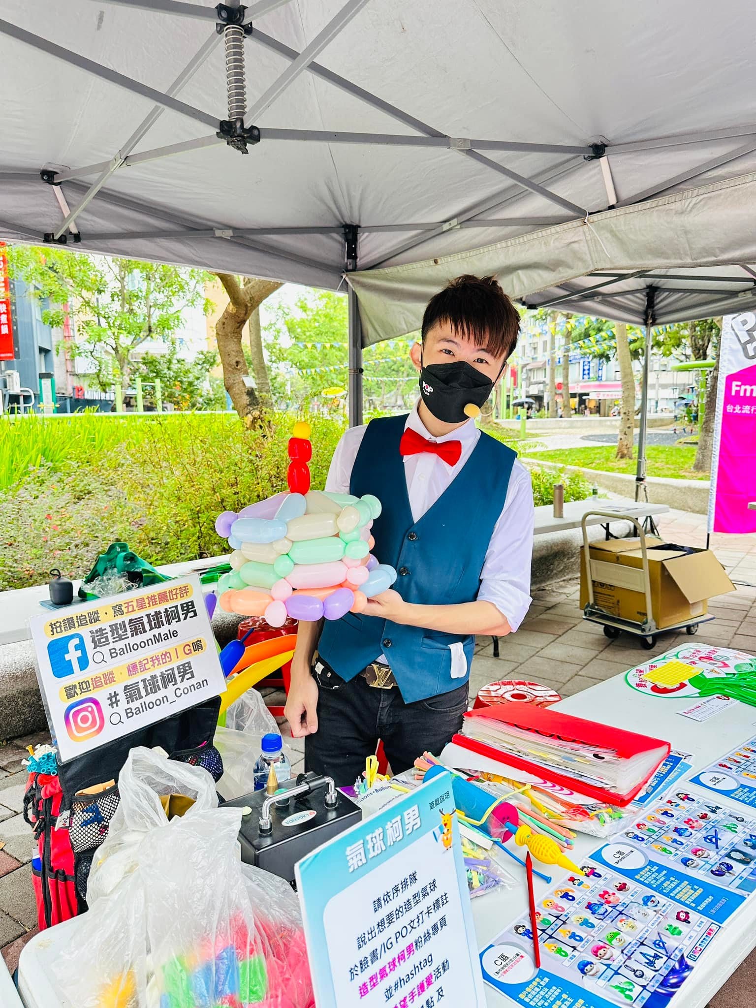 柯男在攤位帳篷下展示馬卡龍色氣球花冠,桌上是造型目錄