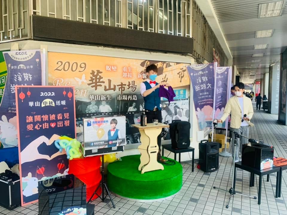 騎樓下的公益募款舞台全景,綠色圓台、木桌與音響設備