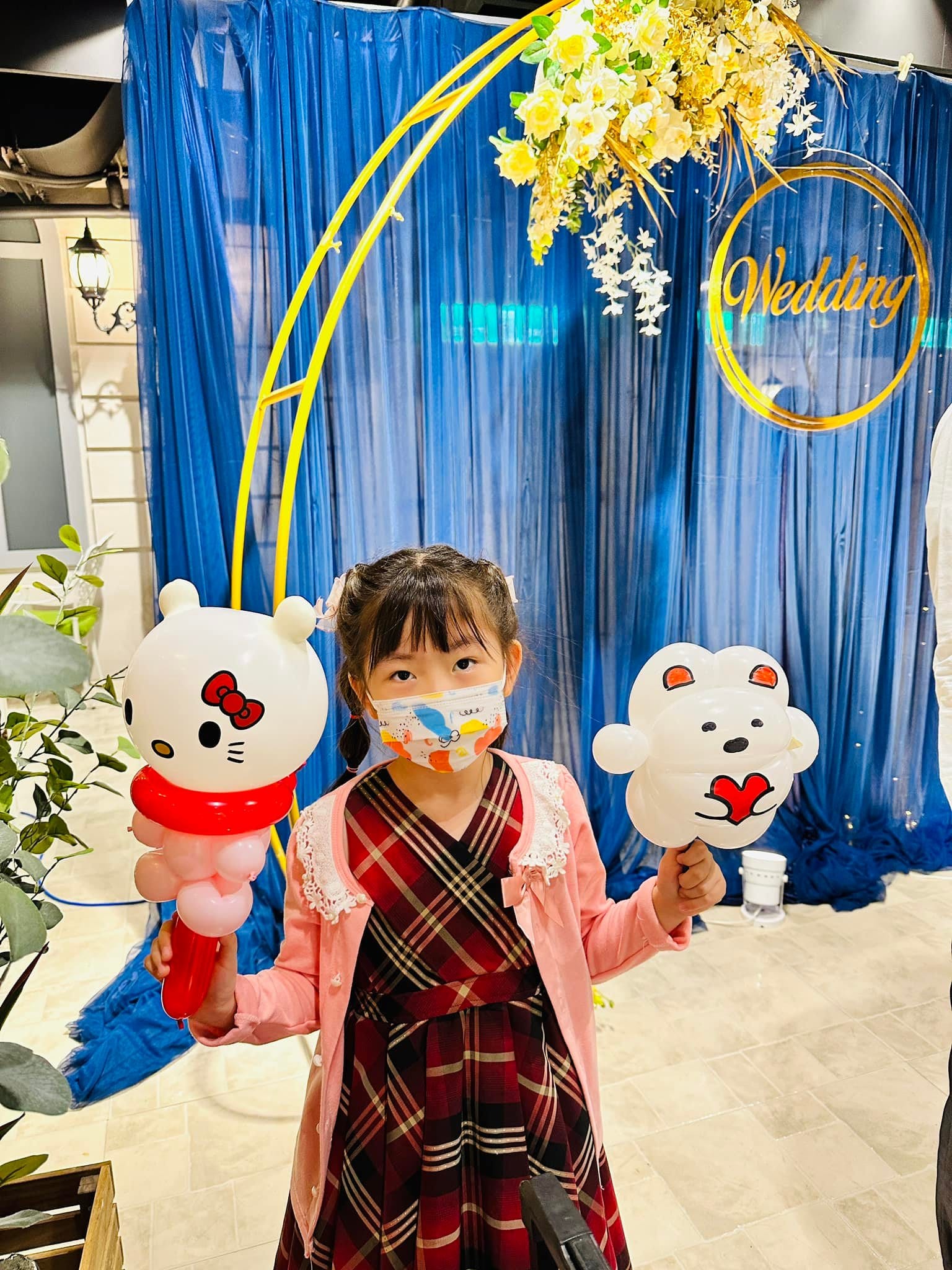 小女孩一手拿 Hello Kitty 氣球,一手拿抱著紅色愛心的白色小熊氣球