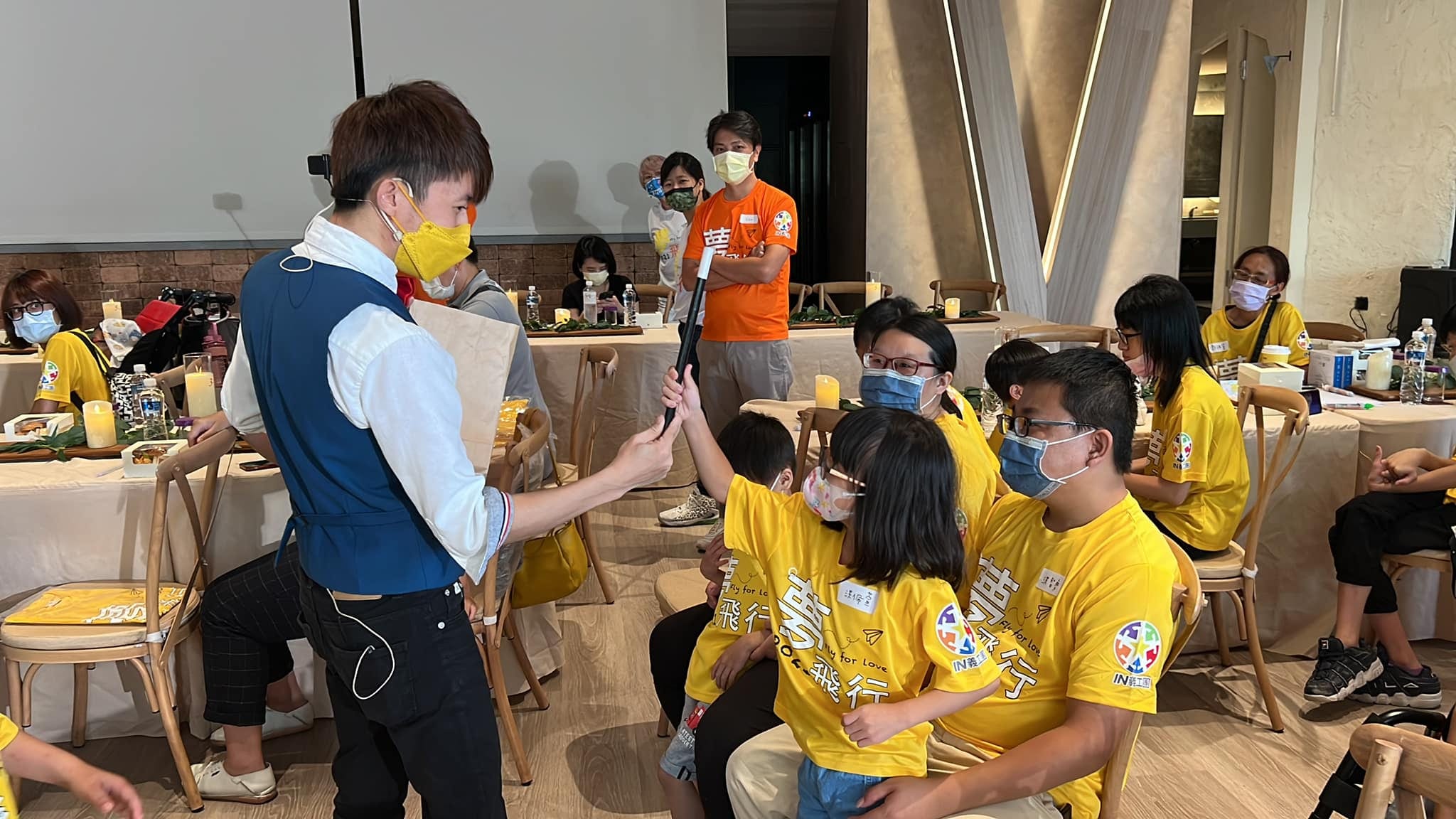 小女孩伸手碰柯男手上的黑色魔術棒，旁邊的爸爸一起看